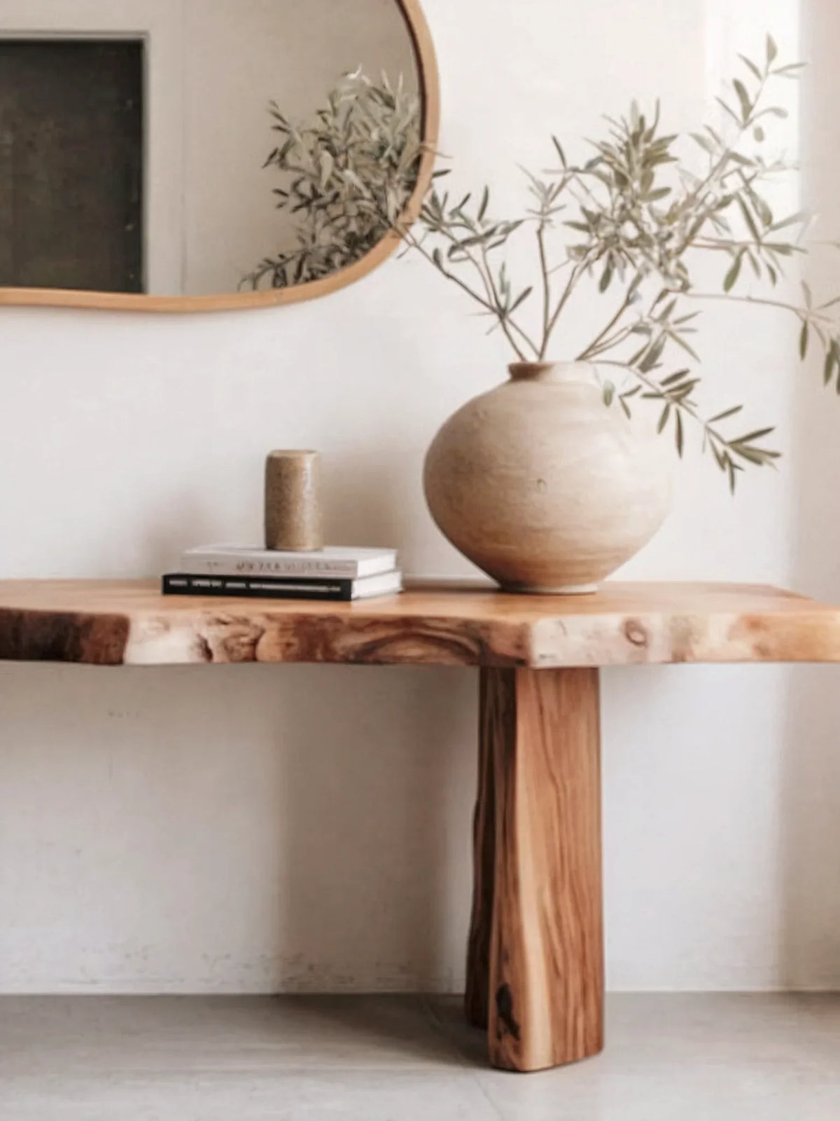 Minimalist entryway with solid wood live edge console table, ceramic vase, and wall mirror.