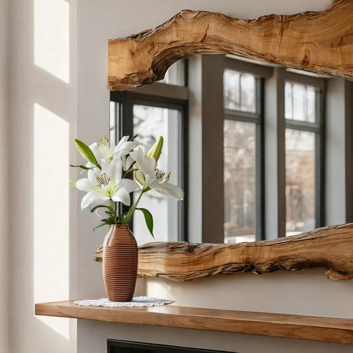 Minimalist interior with a solid wood live edge floating shelf, rustic mirror, and vase of lilies