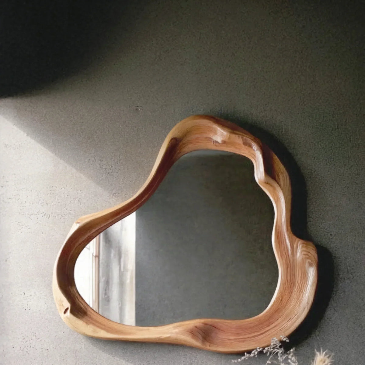 Modern organic-shaped wooden framed mirror on textured wall, artistic home decor