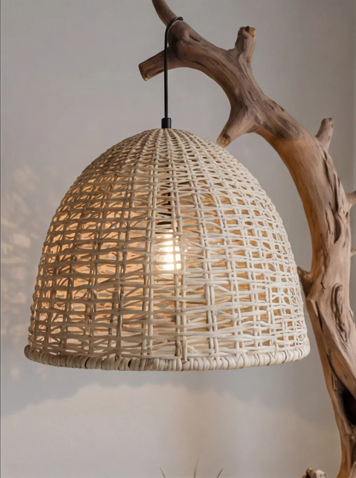 Sustainable rattan pendant lamp on natural wood branch, modern eco-friendly lighting