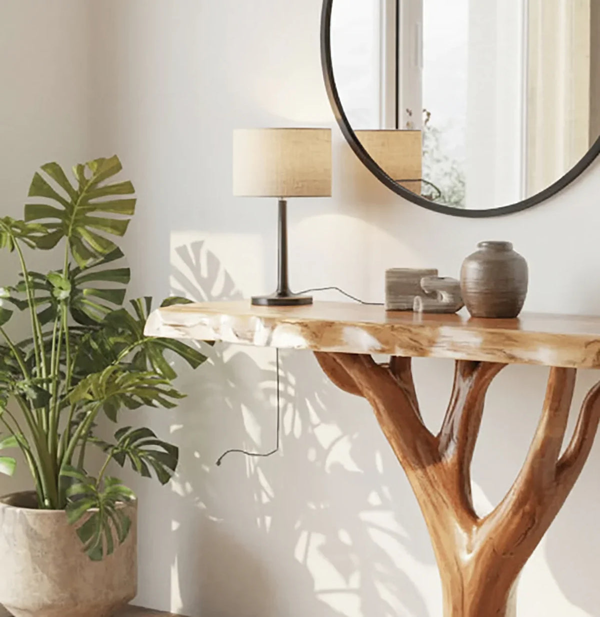 Live edge wood console table with tree branch base, potted plant, lamp, and ceramic decor