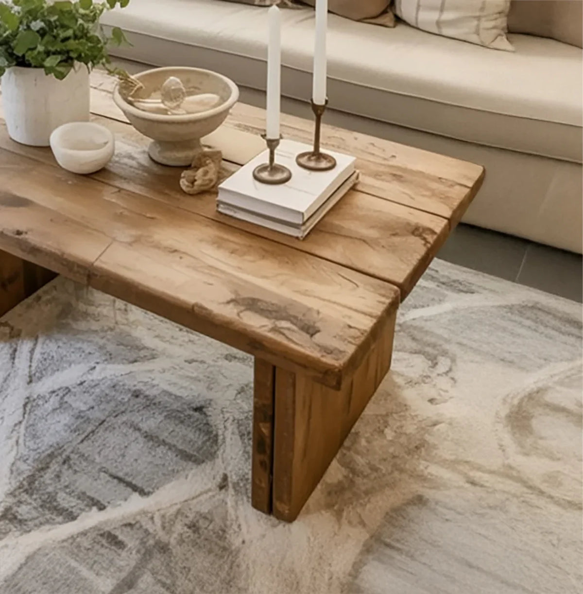 Solid wood rustic coffee table with natural finish, candles, books, and decor in cozy living room