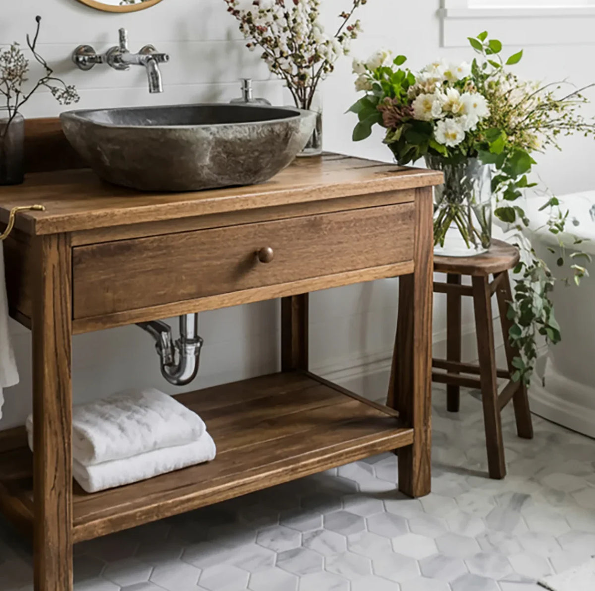 Rustic solid wood bathroom vanity with stone sink, floral decor, and hexagon tile floor