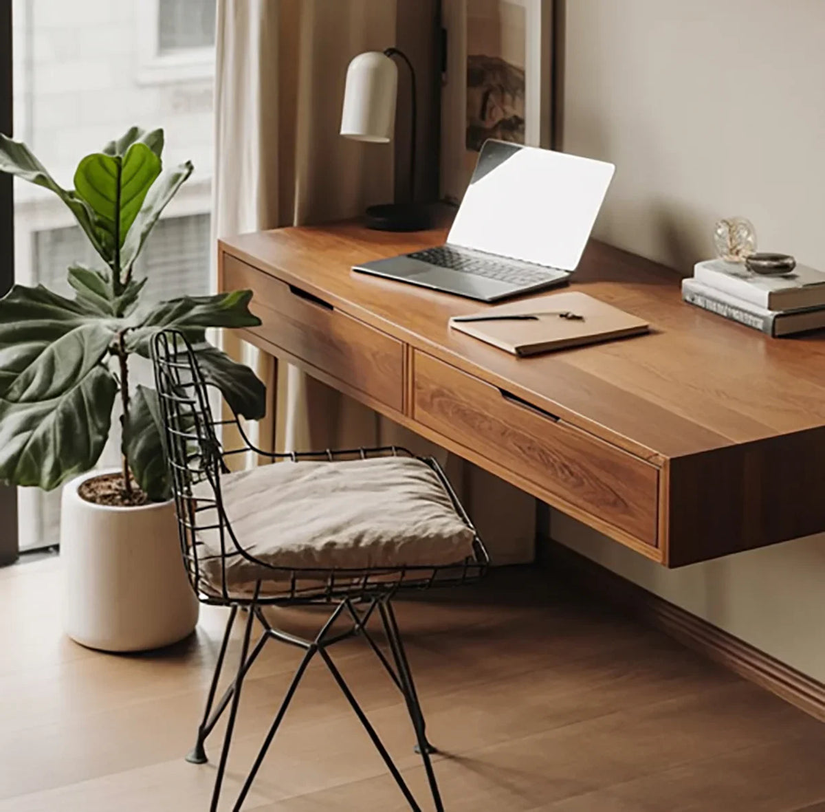 Modern home office with solid wood floating desk, laptop, metal chair, and potted plant