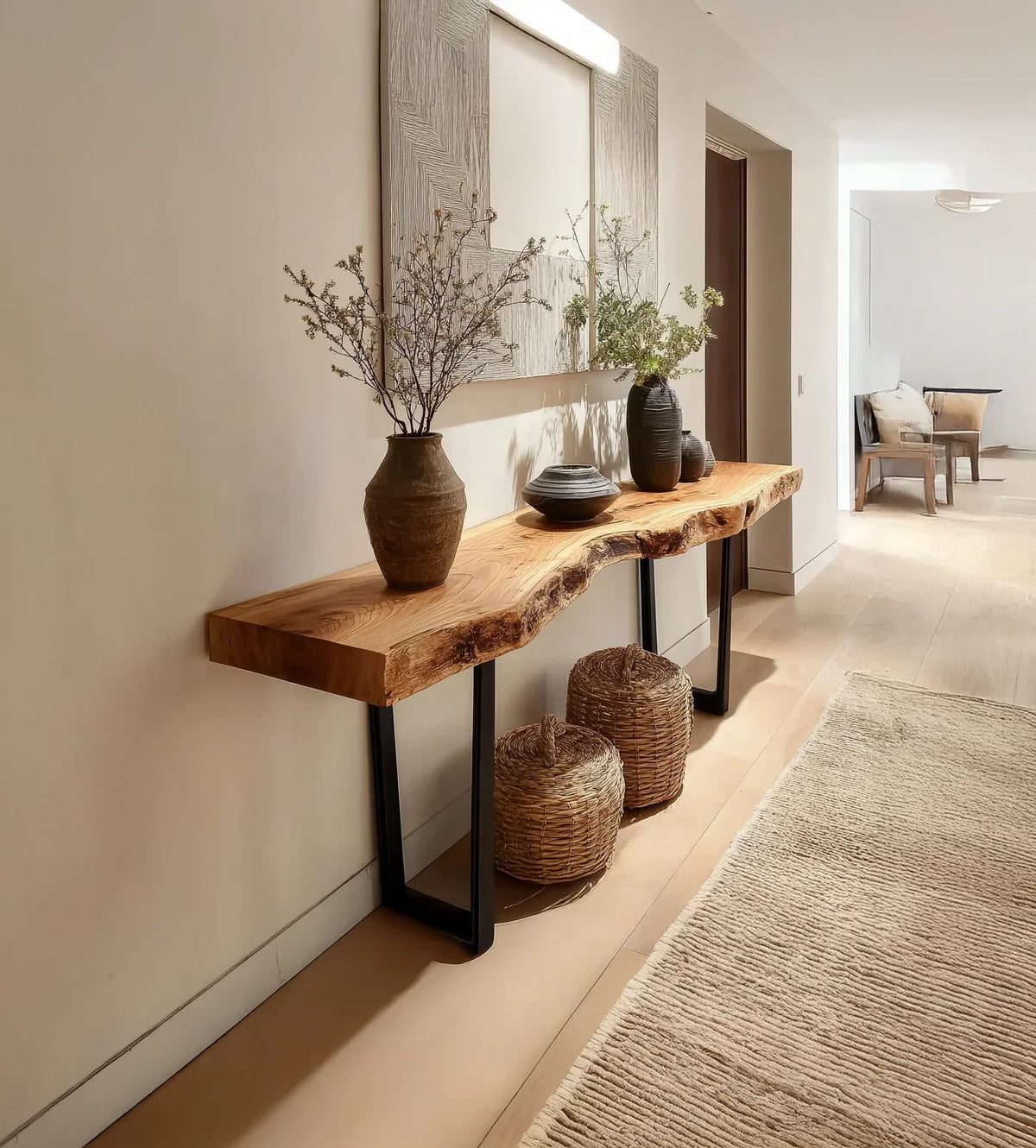 Live edge solid wood console table with black metal legs, decorated with vases, in modern hallway.