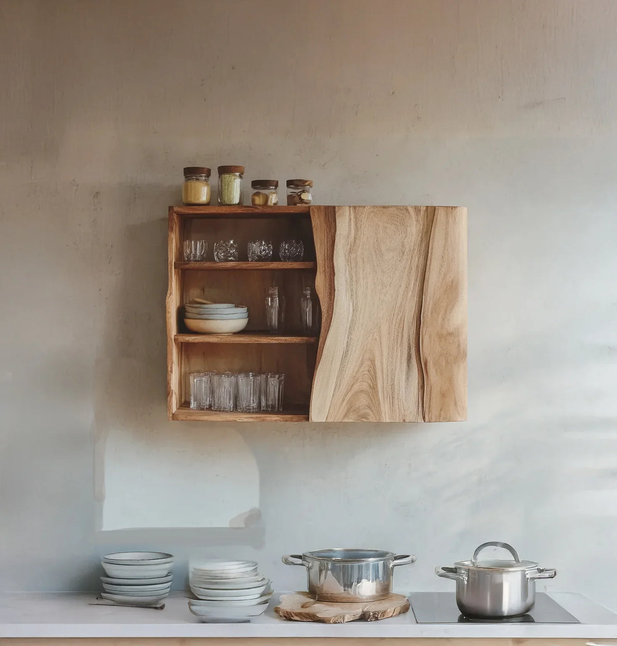 Minimalist kitchen with wooden wall cabinet, glass jars, glasses, bowls, and stainless steel pots