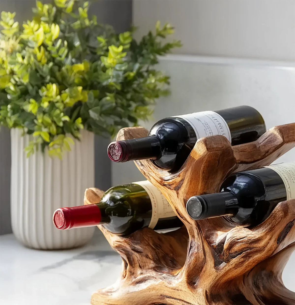 Live edge solid wood wine rack with three wine bottles on marble countertop, indoor decor