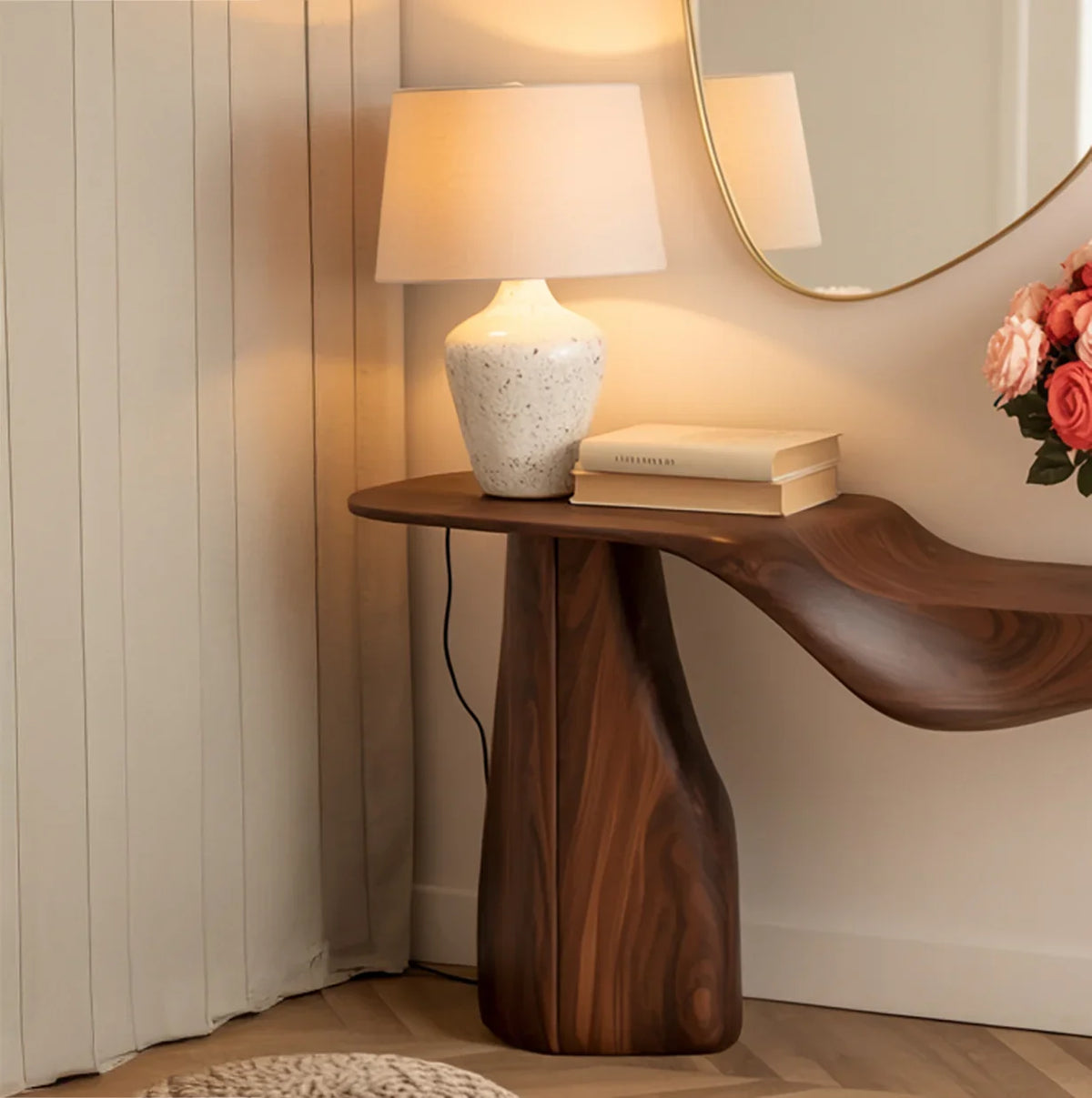 Live edge solid wood console table with sculpted base, lamp, books, and flowers in modern room