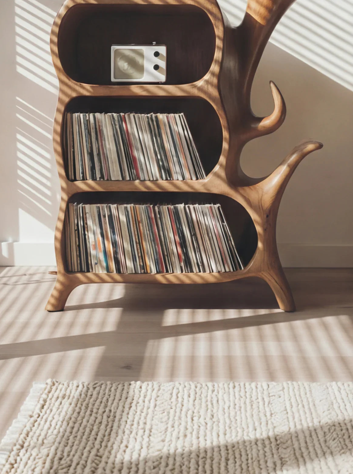 Live edge wood bookshelf with vinyl records and a retro radio, sunlight casting shadows