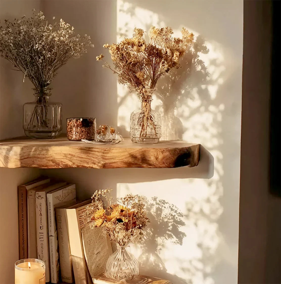 Sunlit wooden shelves with dried floral arrangements, books, and a lit candle in a cozy interior