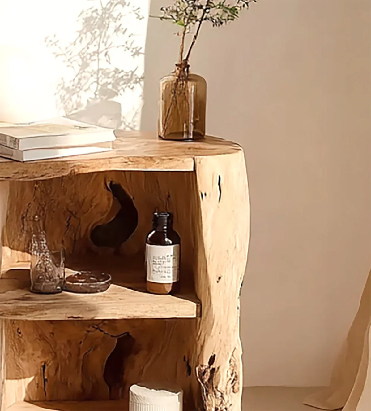 Rustic wooden shelf with amber glass bottle, small vase with plant, books, and decorative objects