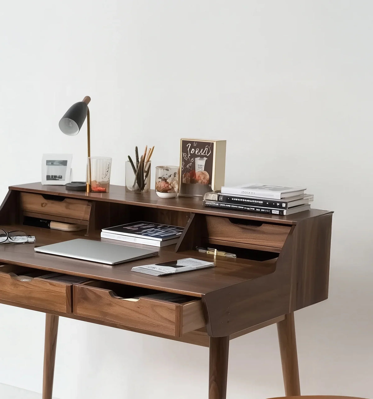 Solid wood writing desk with drawers, books, laptop, and modern lamp in minimal home office