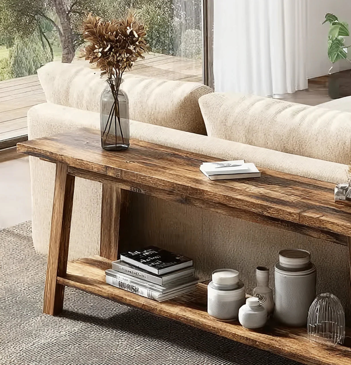 Rustic wooden console table with dried flowers in glass vase, books, and ceramic jars in modern living room