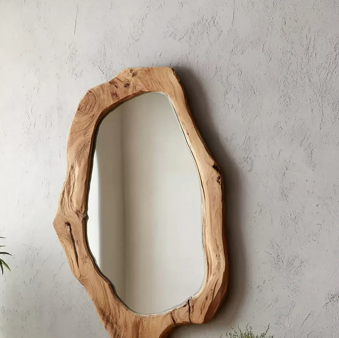 Natural wood frame mirror with irregular shape hanging on textured gray wall
