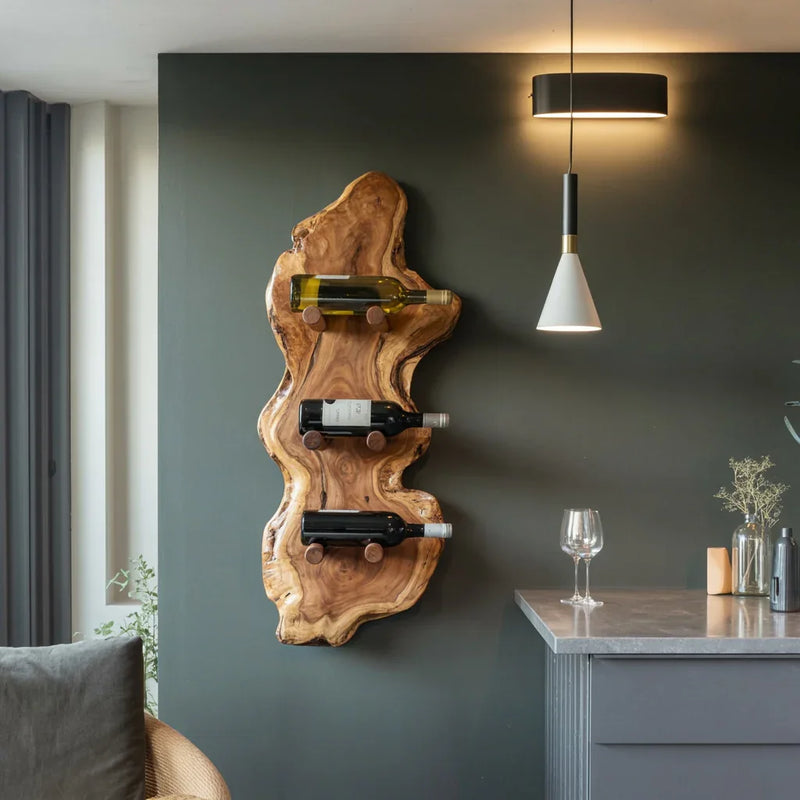 Modern kitchen with live edge wood wine rack holding three bottles against dark green wall