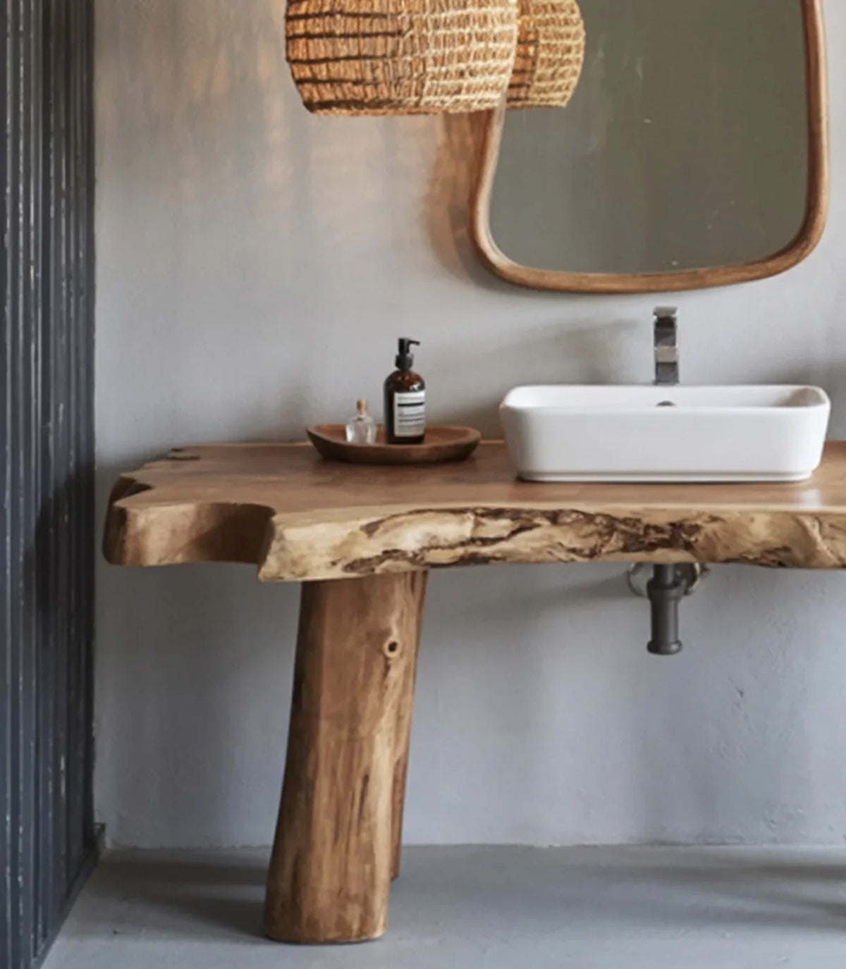 Rustic wooden bathroom vanity with white vessel sink, round mirror, and wicker pendant lights
