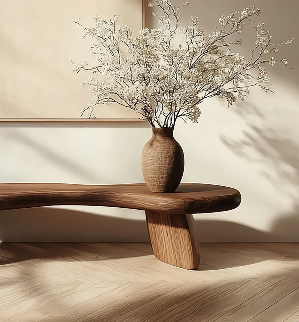 Wooden table with textured brown vase holding delicate white dried flowers in minimalist room