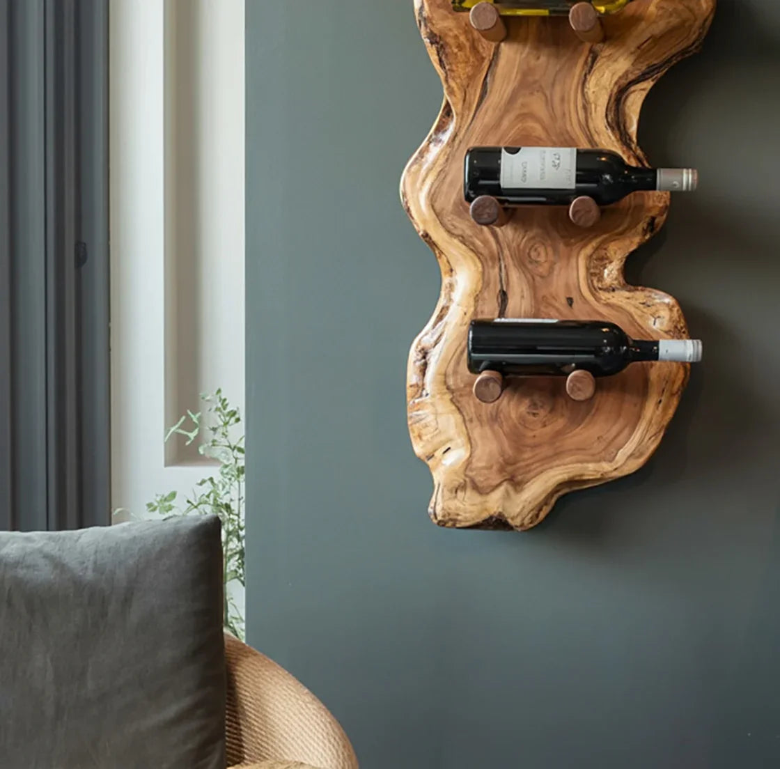 Natural wood wall-mounted wine rack holding two bottles on gray wall in cozy living room