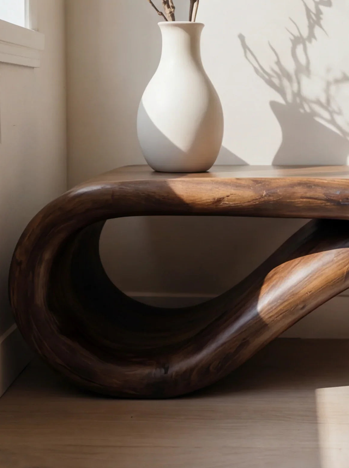 Curved solid wood bench with live edge and ceramic vase in natural sunlight
