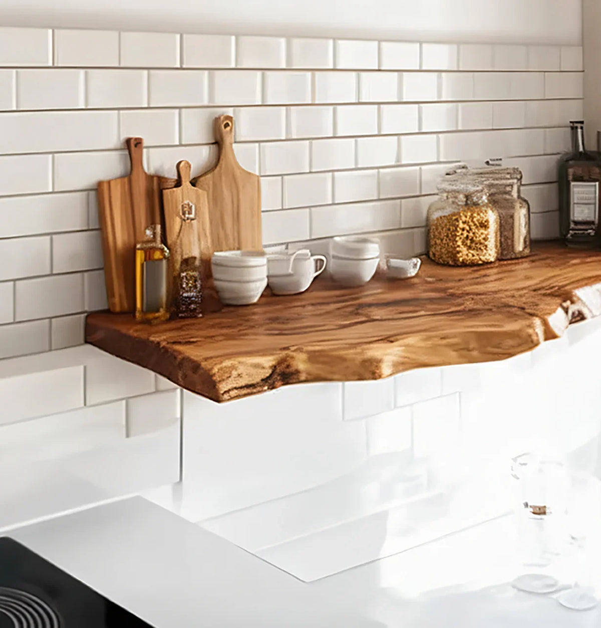 Live edge wood floating shelf in kitchen with cutting boards, jars, and white tile backsplash