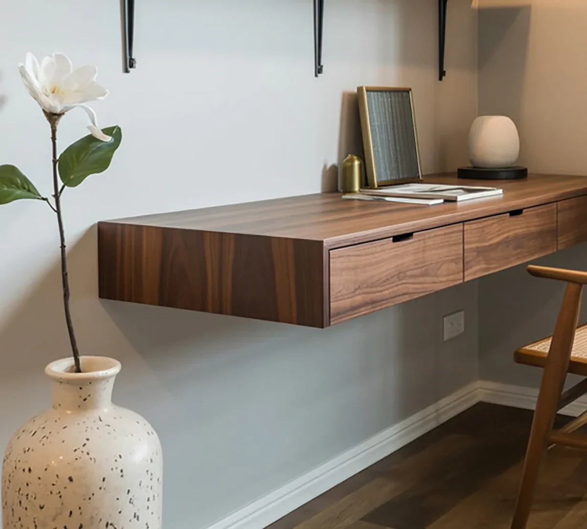 Modern floating wooden desk with drawers, styled with decor in a minimalist home office