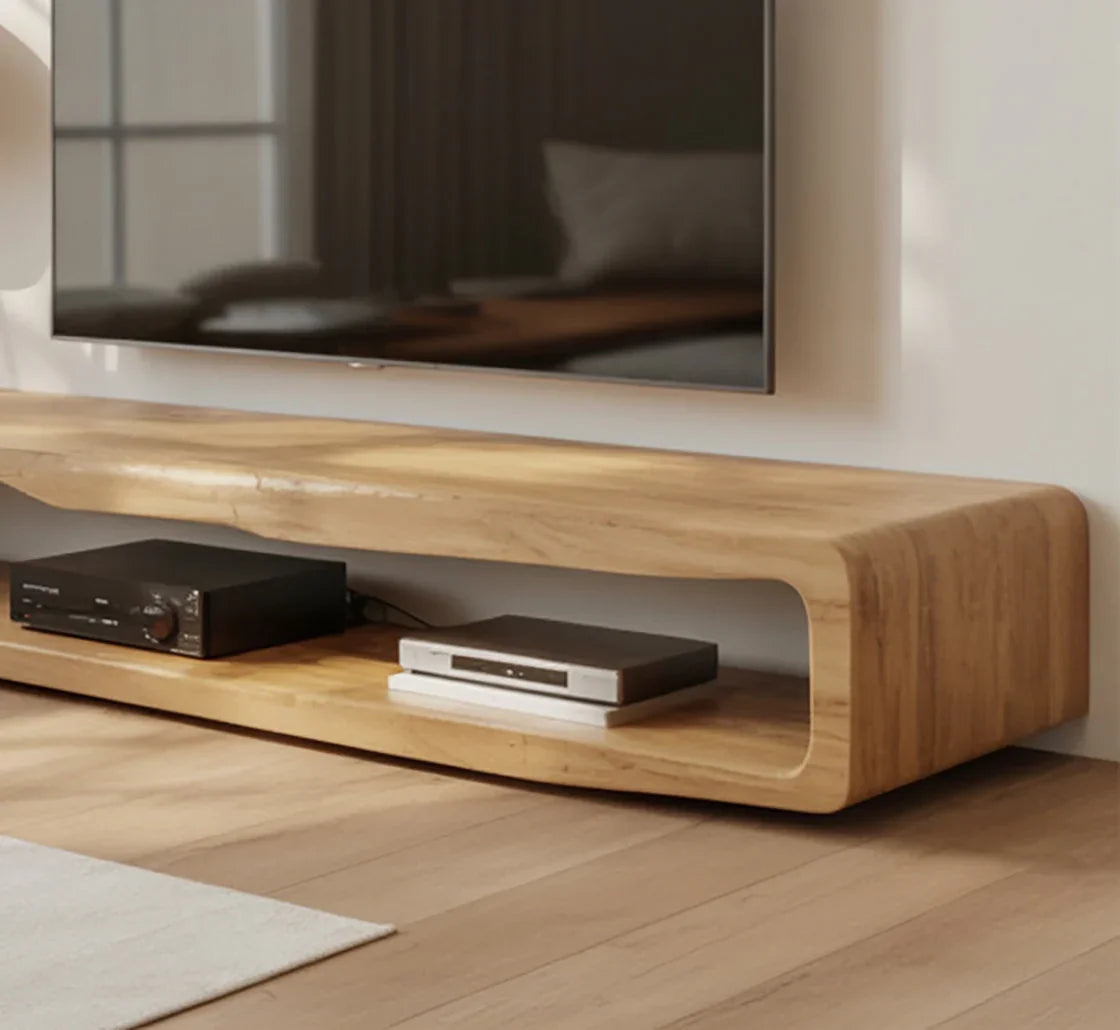 Modern wooden floating TV stand with rounded edges holding audio and media devices under wall-mounted flat-screen