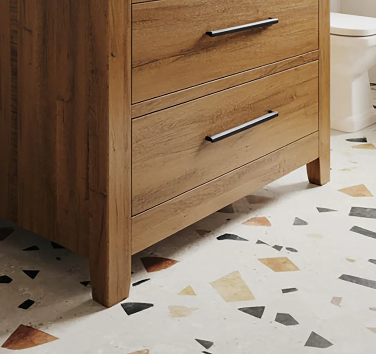 Solid wood cabinet with black handles on a terrazzo tile floor in a bathroom