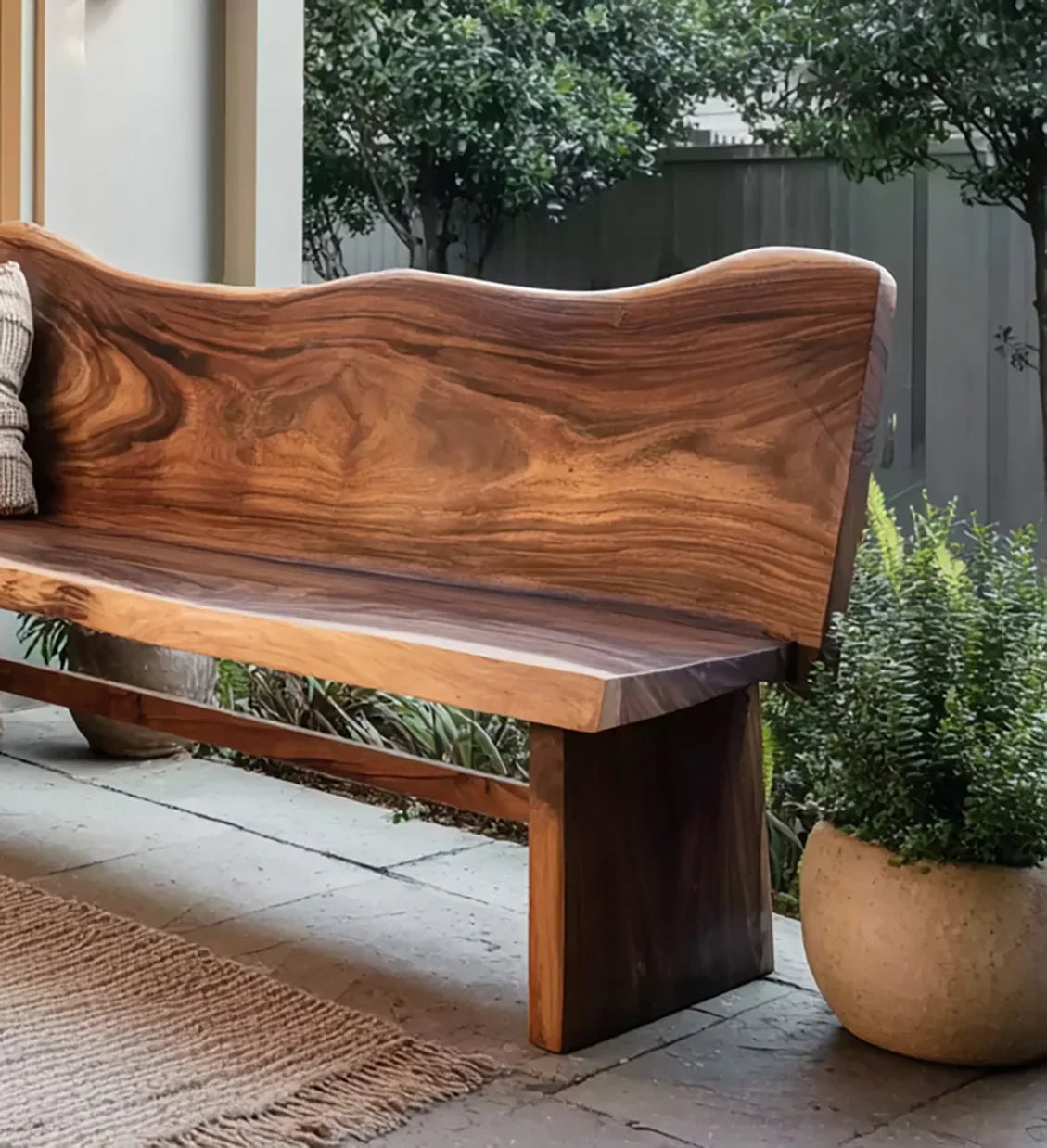 Live edge wooden bench with natural grain in an outdoor patio garden with potted plants