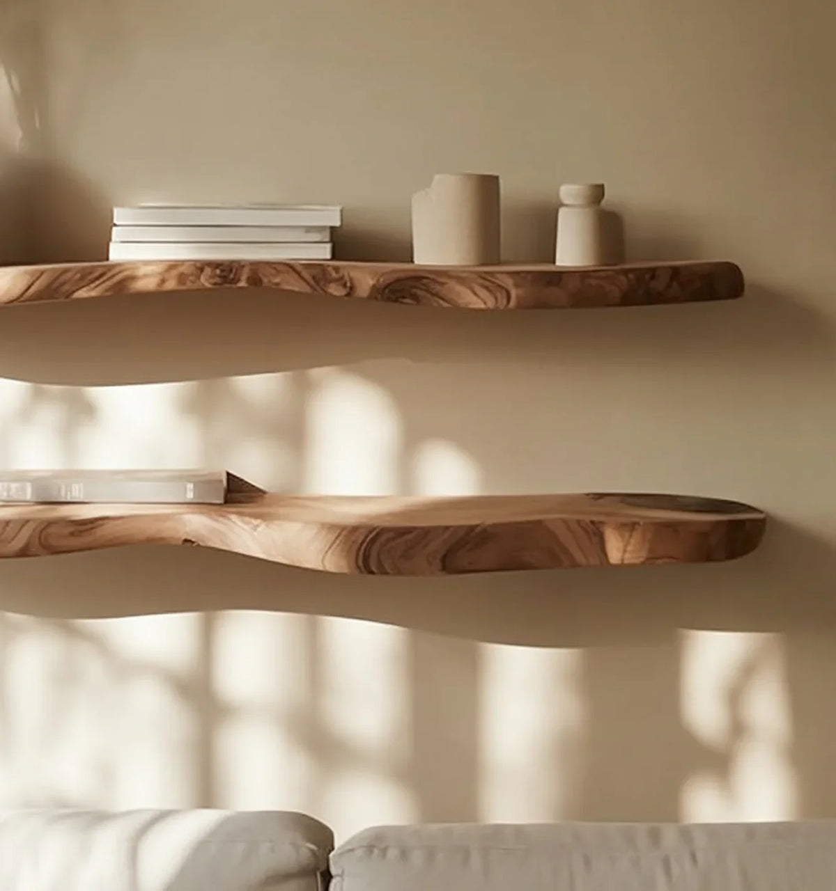 Live edge solid wood floating shelves with books and decor on beige wall above sofa