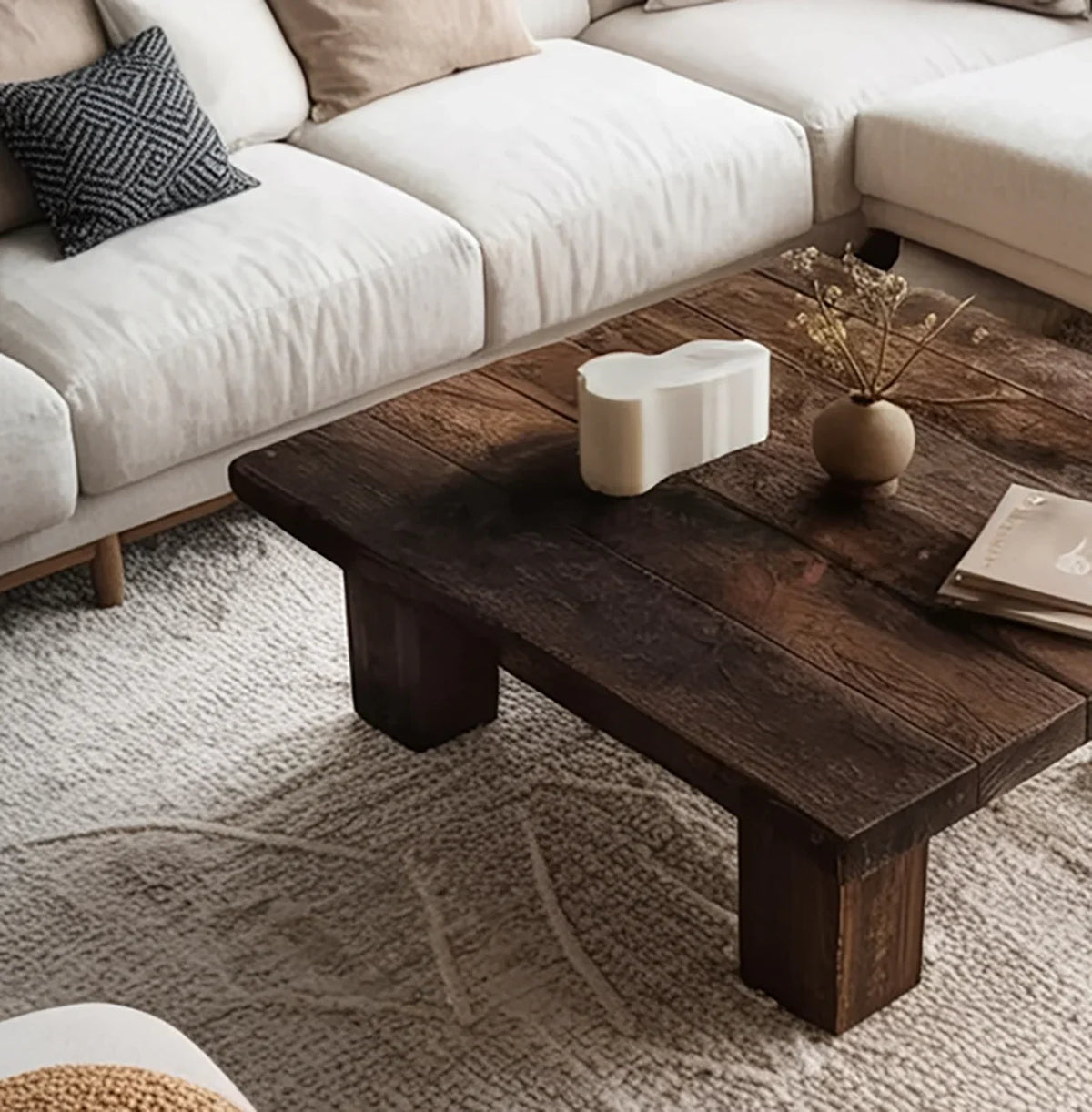 Rustic solid wood coffee table in modern living room with cream sectional sofa and textured rug