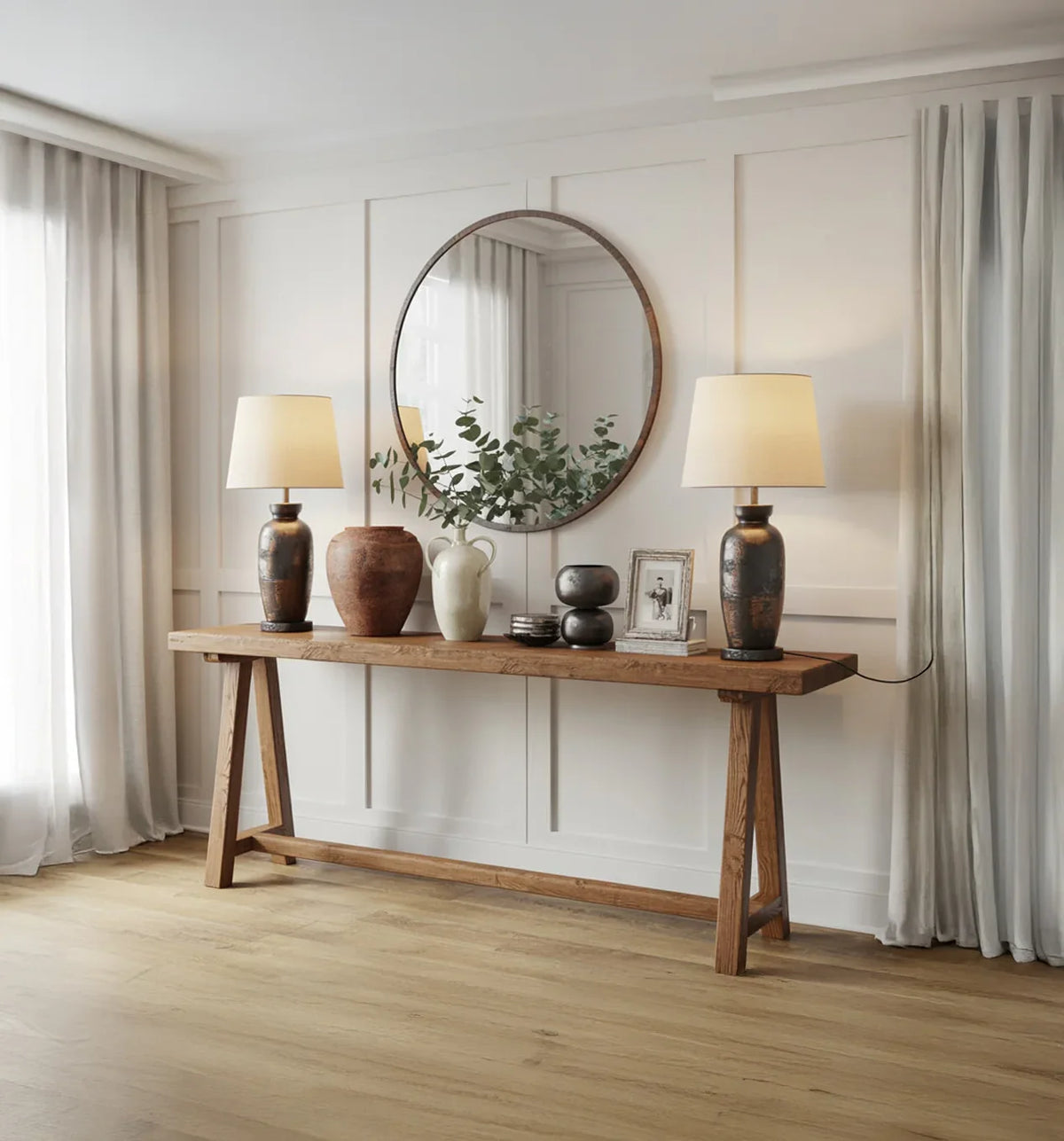 Modern console table with ceramic lamps, decorative vases, framed photo, and round wall mirror