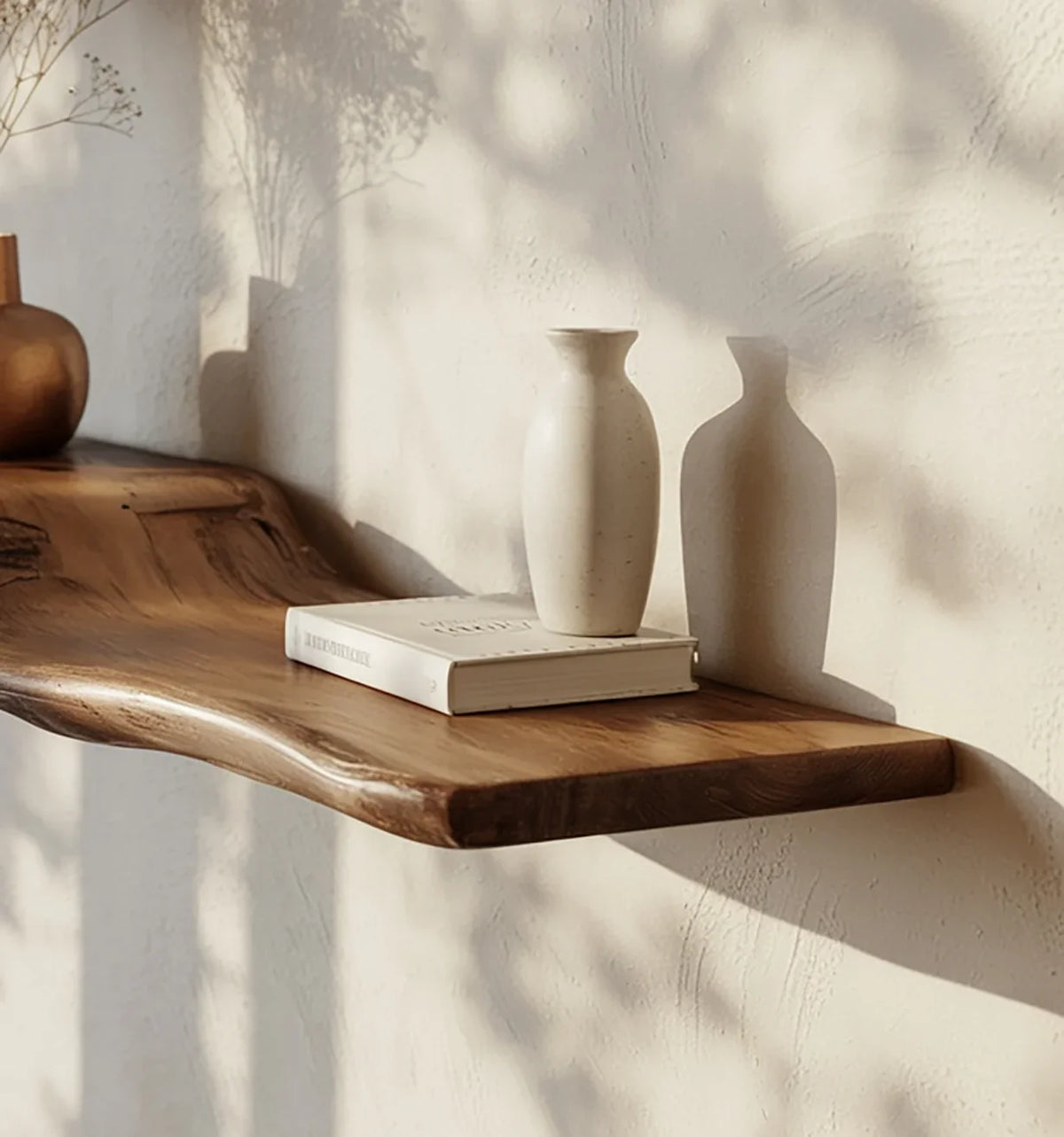 Live edge wooden floating shelf with ceramic vase and book, sunlight on textured wall