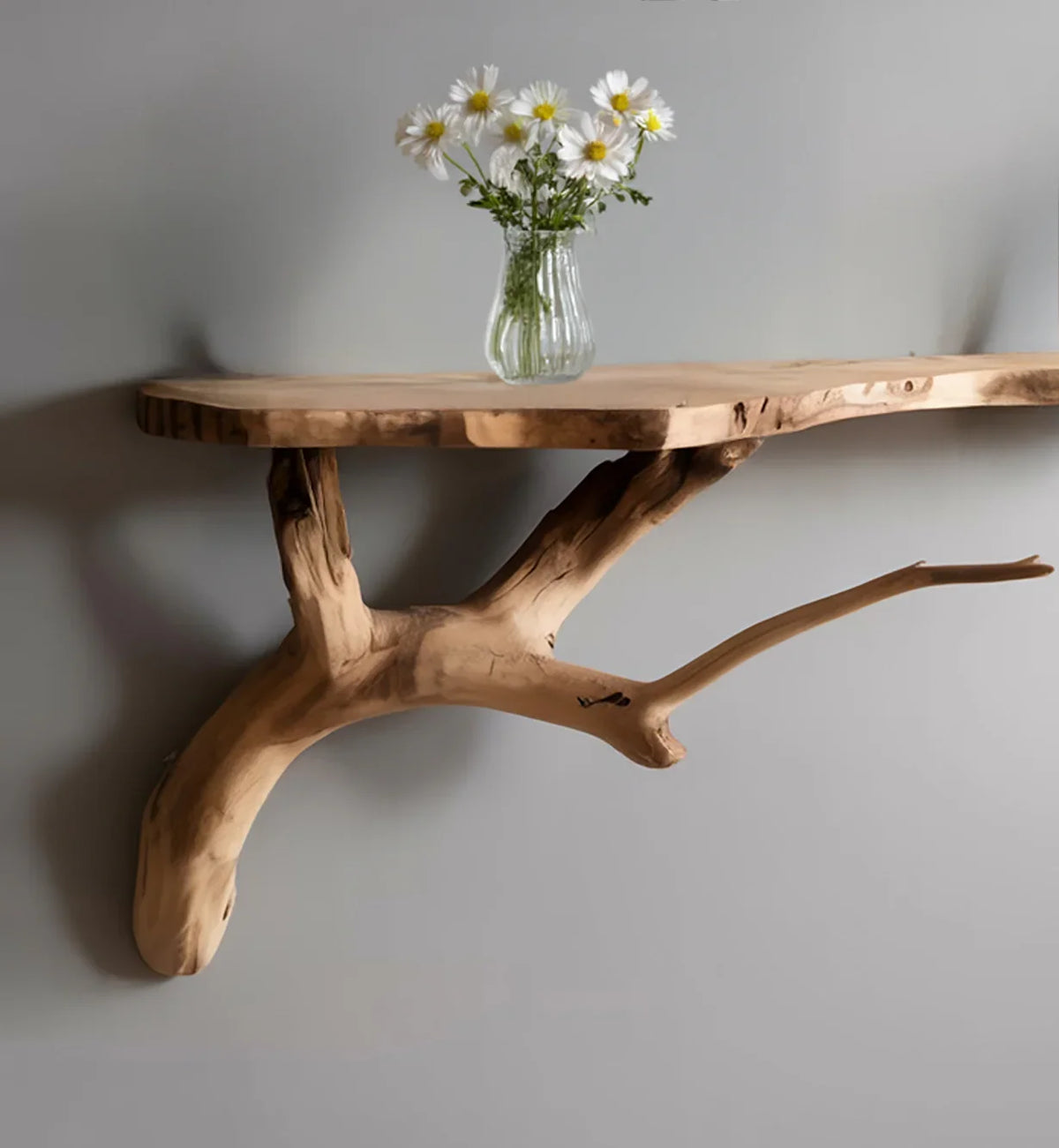 Live edge floating wood shelf with branch support and vase of daisies, wall mounted.