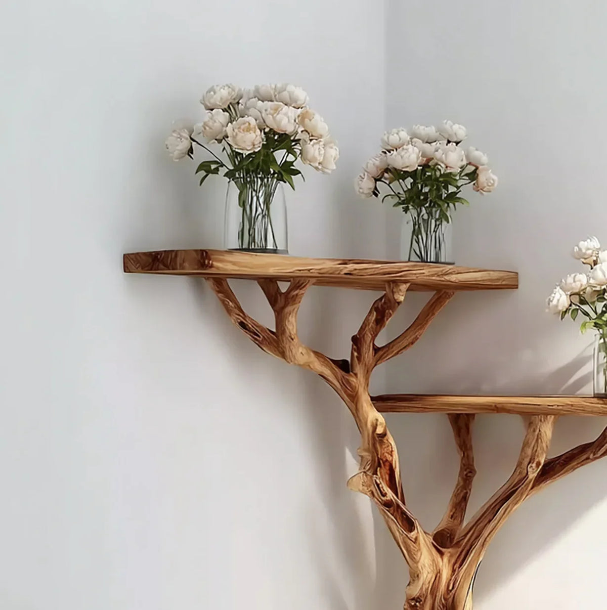 Solid wood tree bookshelf with live edge shelves and vases of white flowers in a modern room