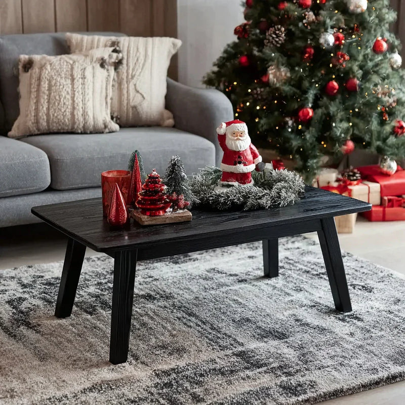 Cozy living room with dark wood coffee table decorated with Santa figurine, mini trees, and red candles