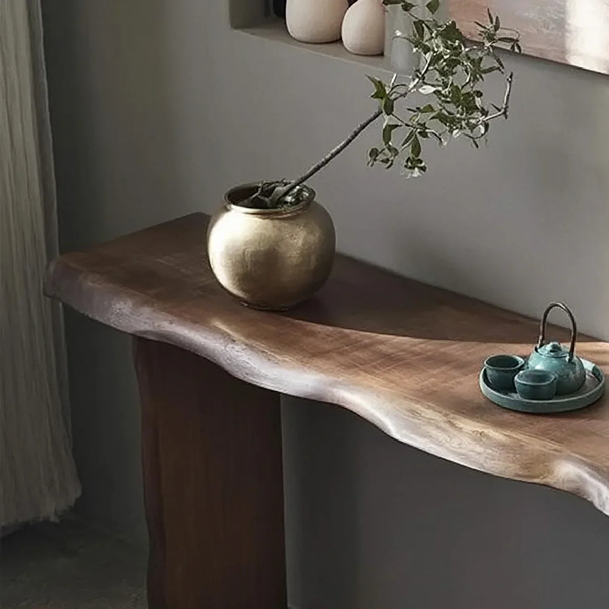 Solid wood live edge console table with a gold vase and green ceramic tea set