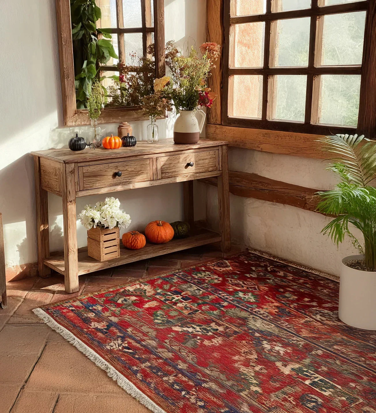 Rustic solid wood console table with fall decor and pumpkins, red patterned rug, large window