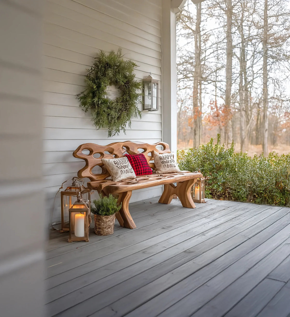 Rustic wooden bench with cushions and wreath on white porch with lanterns and autumn trees