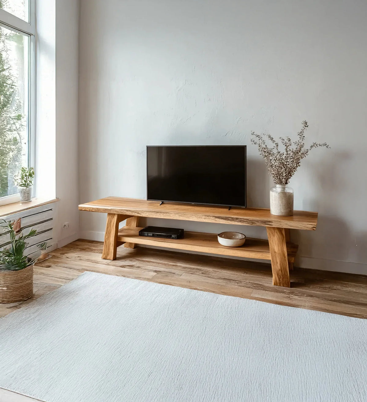 Minimalist living room with wooden TV stand, flat screen TV, and dried flower vase