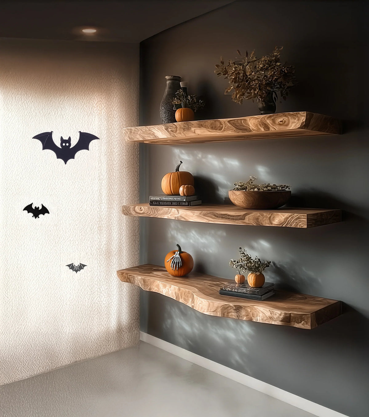 Modern floating wood shelves decorated with pumpkins, dried flowers, Halloween bats on curtain