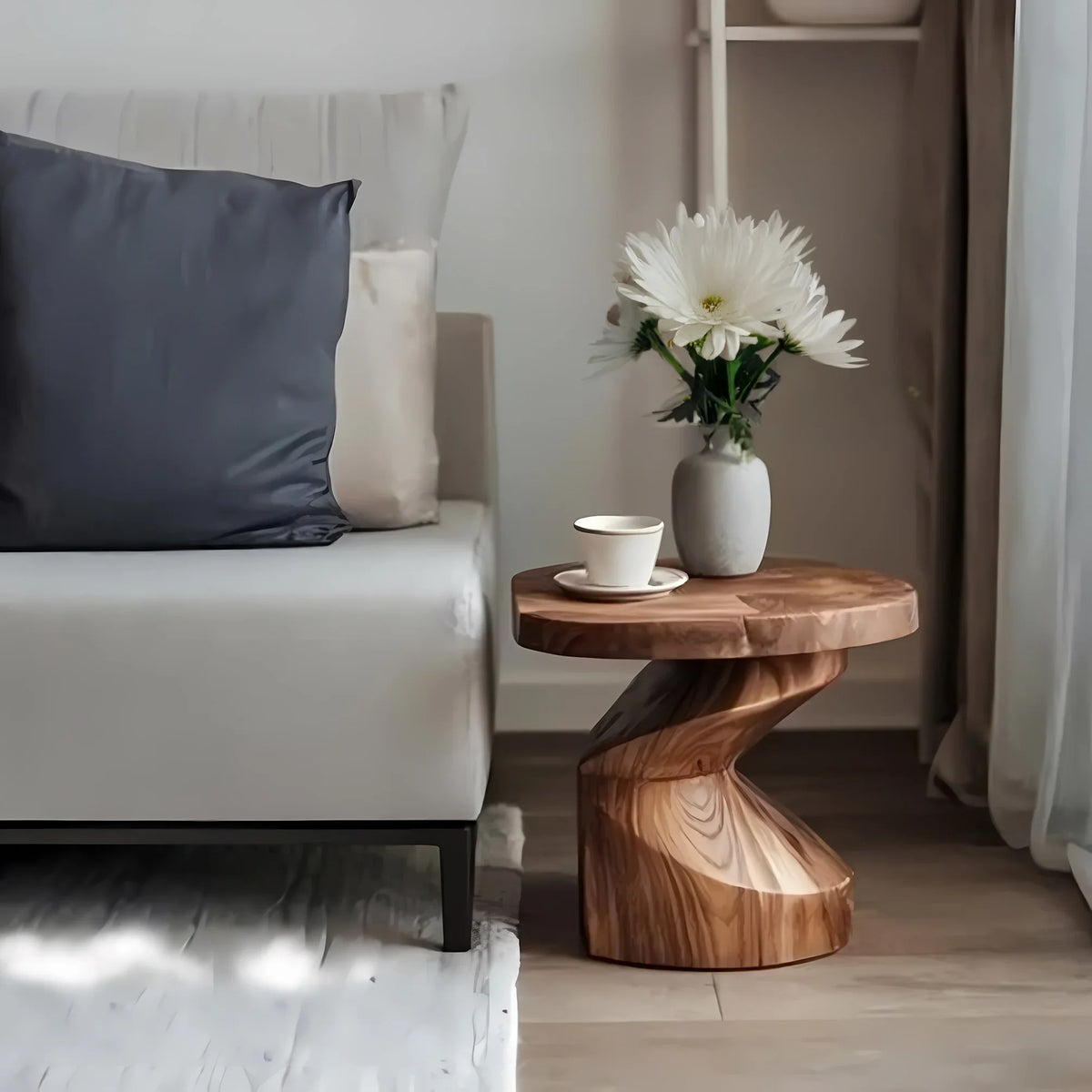 Modern living room with white sofa, dark pillow, wooden twisted side table, white vase with flowers, and coffee cup