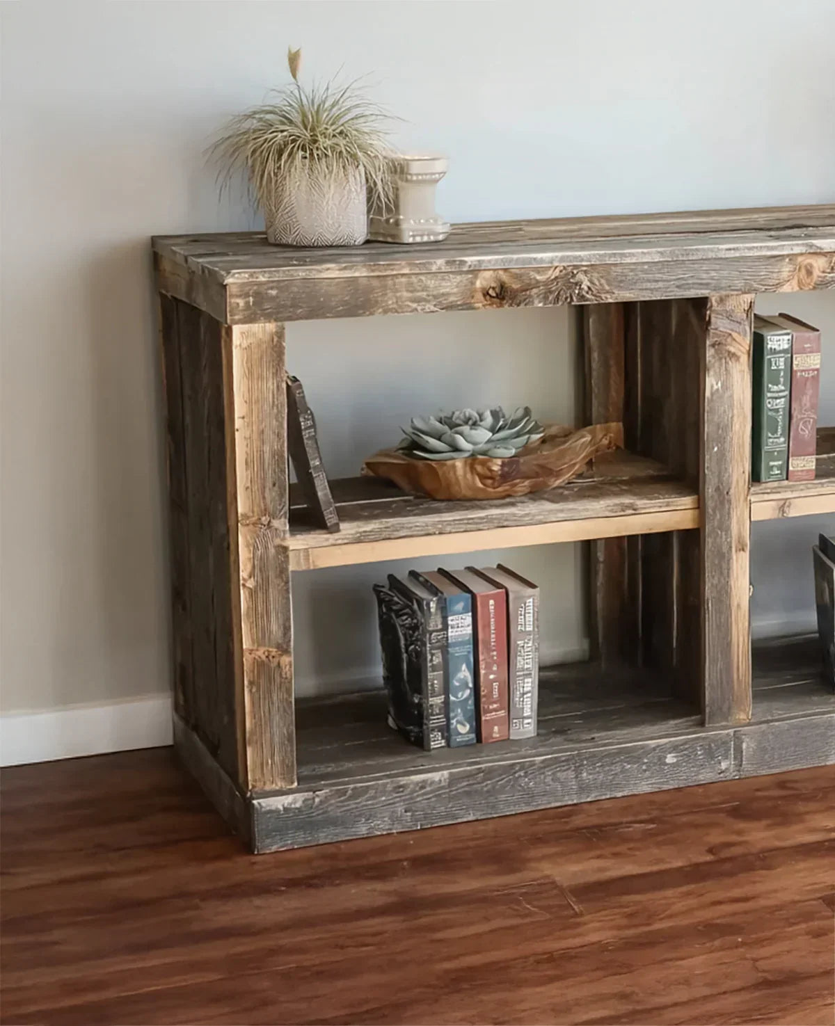 Rustic solid wood bookshelf with books, potted plants, and a decorative succulent bowl.