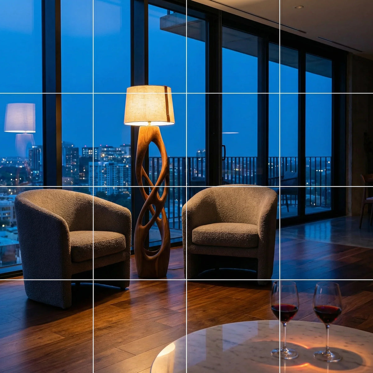 Modern penthouse living room with city view, two armchairs, sculptural wood lamp, and wine glasses