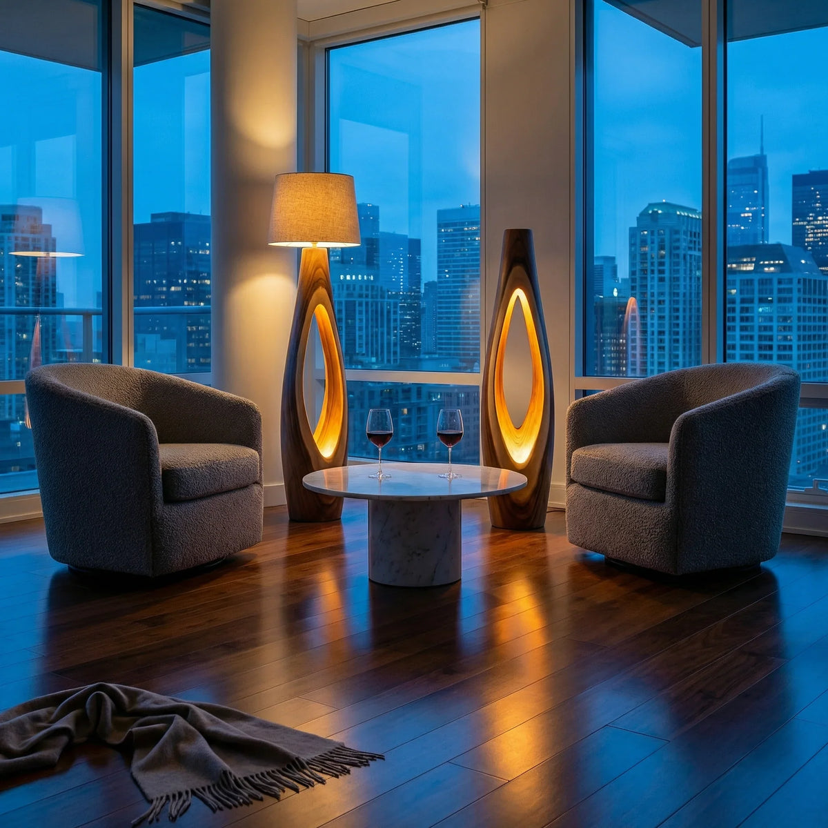 Modern penthouse living room with city view, cozy armchairs, marble table, and wood lamps.
