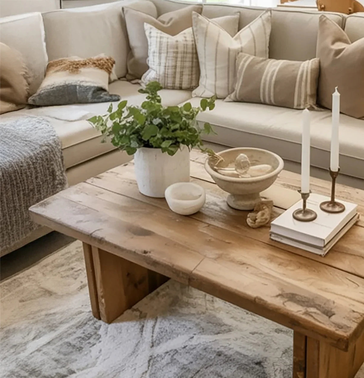 Solid wood coffee table with plant, candles, and decor in a cozy living room with beige sofa