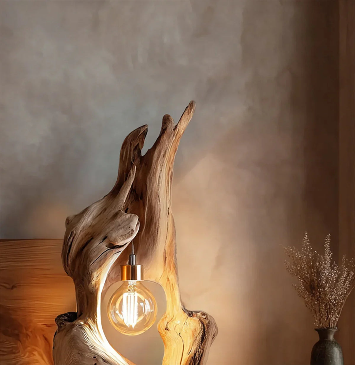 Rustic wooden lamp with glowing filament bulb and dried flowers in vase on textured wall
