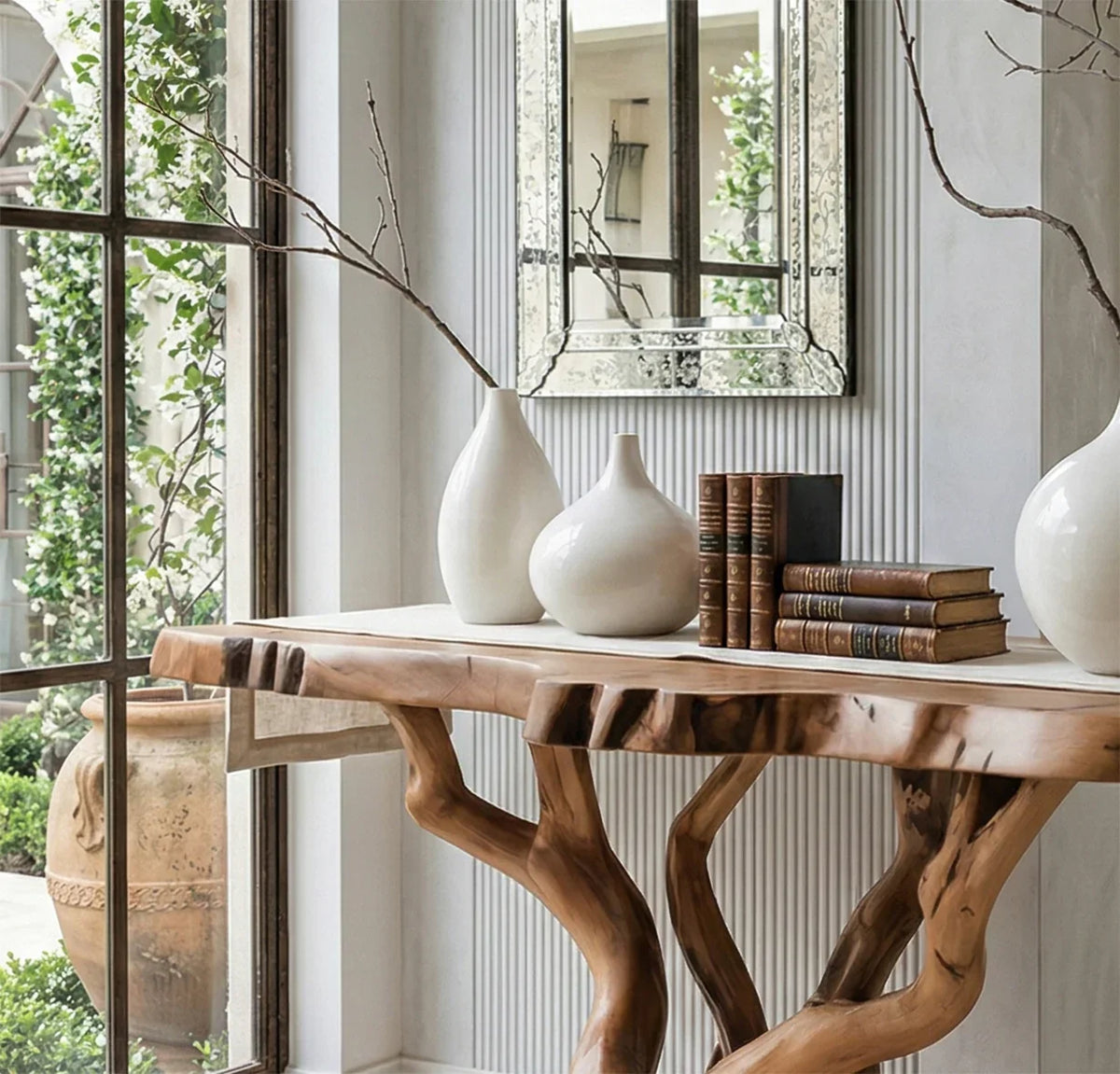 Live edge solid wood console table with natural branch legs, ceramic vases, and vintage books