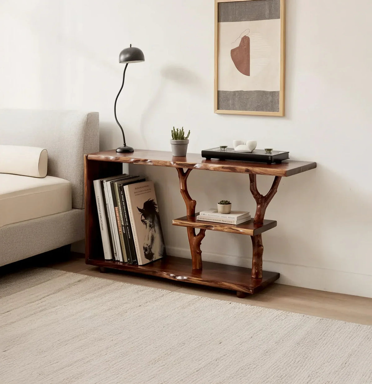 Live edge solid wood console table with tree branch shelves, styled with books, plants, and decor in a modern living room.