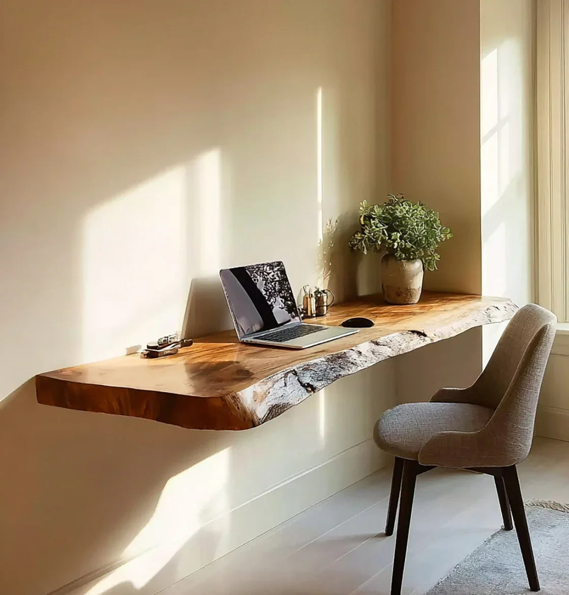 Live edge floating wood desk with laptop, plant, and chair in a sunlit home office.