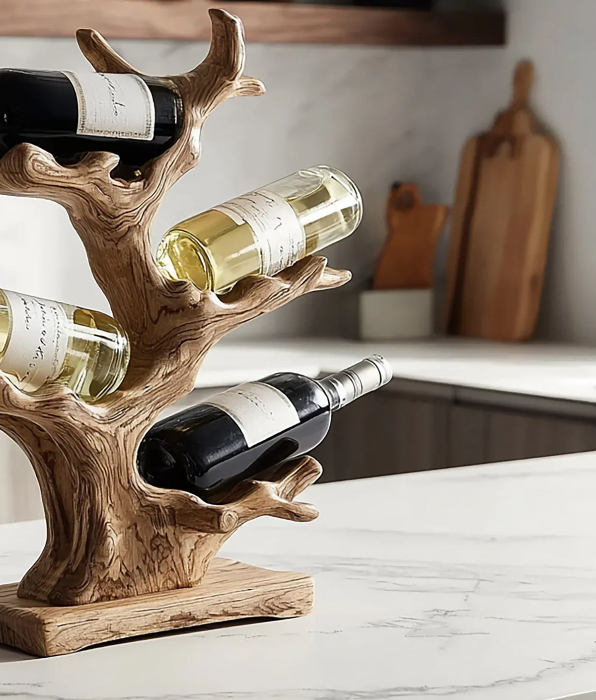 Wooden tree-shaped wine rack holding three bottles of red and white wine on marble kitchen countertop